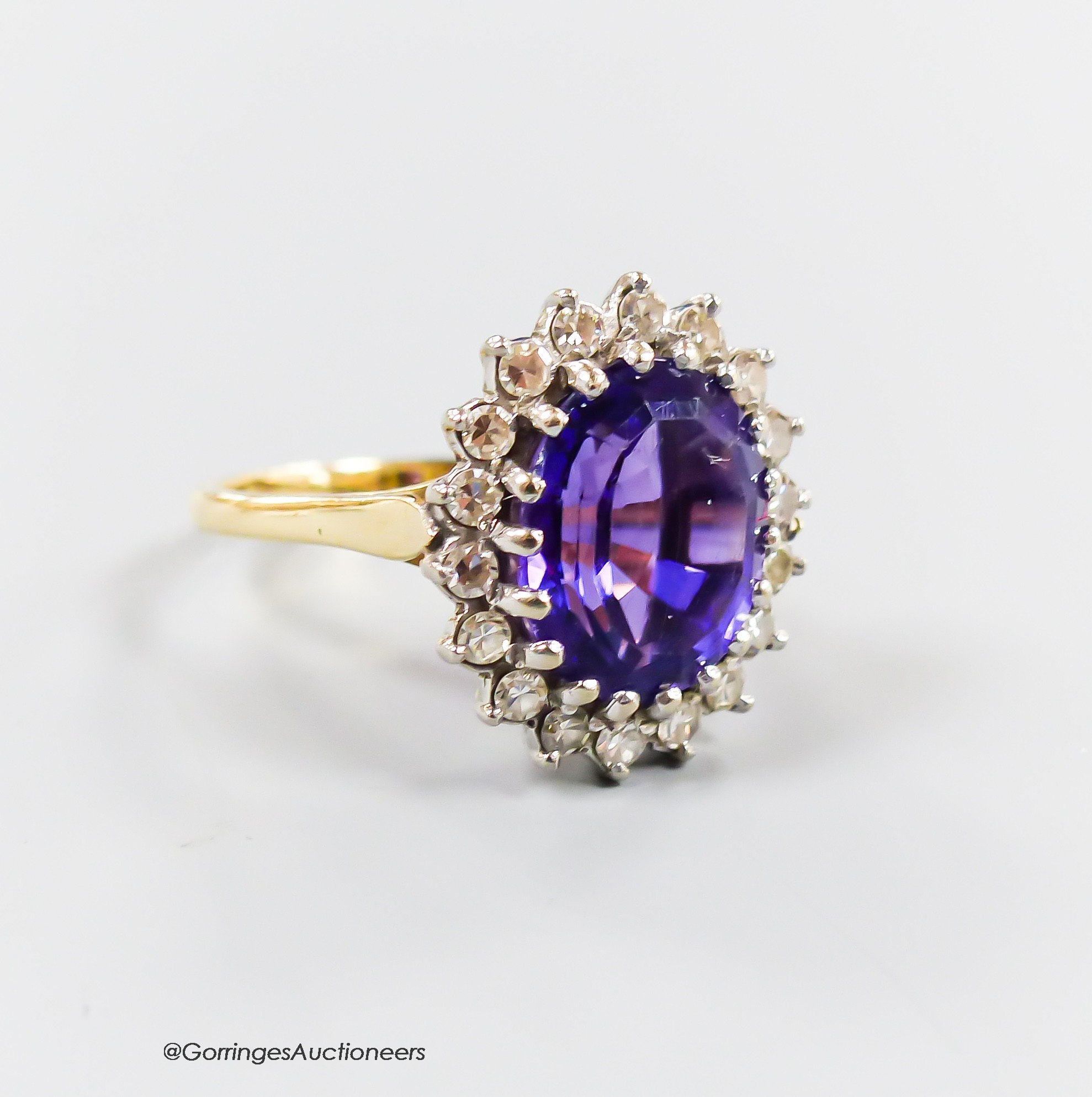 A modern yellow metal, amethyst and diamond set oval cluster ring, size O, gross 5.6 grams.
